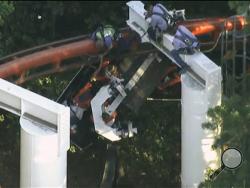 In this frame grab from video made on Monday, July 7, 2014 and provided by KTLA-News, workers at the Six Flags Magic Mountain amusement park rescue people trapped on the Ninja roller coaster after a tree fell onto the tracks, dislodging the front car. The accident left four people slightly injured and kept nearly two-dozen others hanging 20 to 30 feet in the air for hours as day turned to night. Two of the four injured people were taken to a hospital as a precaution, but all the injuries were minor, fire an