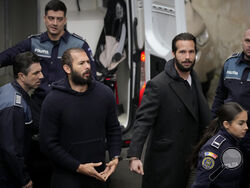 FILE- Police officers escort Andrew Tate, center, handcuffed to his brother Tristan Tate, to the Court of Appeal in Bucharest, Romania, Monday, Feb. 27, 2023. (AP Photo/Andreea Alexandru, File)