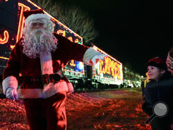 Santa Claus waves to children during a visit of the CSX Holiday Express Thursday, Nov. 21, 2024, in Erwin, Tenn. The railway company held a celebration and concert for the town affected by Hurricane Helene. (AP Photo/George Walker IV)