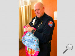 In this photo taken Dec. 14, 2018, paramedic Mickey Huber holds 2-day-old baby Zoele Mickey Skinner at Enloe Medical Center in Chico, Calif. The newborn's middle name is named after Huber, who helped her mother, Anastasia Skinner, who went into premature labor while trying to escape a terrifying wildfire that wiped out the Northern California town of Paradise. After getting Skinner to an ambulance, Huber helped with the mass evacuation until the next day. (Daniel Skinner via AP)
