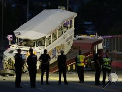 Police officers and other officials watch as a "Ride the Ducks" tourist vehicle is loaded onto a flatbed tow truck in the late evening Thursday, Sept. 24, 2015, after it was involved in a fatal crash with a charter passenger bus earlier in the day in Seattle. (AP Photo/Ted S. Warren)