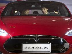 In this Monday, April 25, 2016, file photo, a man sits behind the steering wheel of a Tesla Model S electric car on display at the Beijing International Automotive Exhibition in Beijing. Federal officials say the driver of a Tesla S sports car using the vehicle’s “autopilot” automated driving system has been killed in a collision with a truck, the first U.S. self-driving car fatality. 