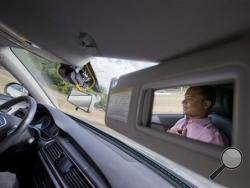 Kaushik Raghu, Senior Staff Engineer at Audi, is reflected in the passenger side visor mirror while demonstrating an Audi self driving vehicle on I-395 expressway in Arlington, Va., Friday, July 15, 2016. (AP Photo/Pablo Martinez Monsivais)