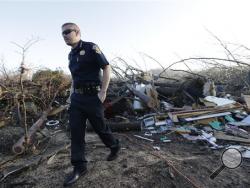 Interim Sheriff Nick Weems of the Perry County Sheriff's Department looks over debris Thursday, Dec. 24, 2015, near Linden, Tenn. Several people were killed in Mississippi, Tennessee and Arkansas as spring-like storms mixed with unseasonably warm weather spawned rare Christmastime tornadoes in the South. (AP Photo/Mark Humphrey)