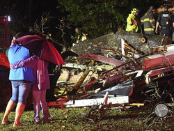 Bystanders hug as first responders work to free a victim after a tree fell on a house in Natchez, Miss., Saturday, Dec. 28, 2024. (Thomas Graning/The Natchez Democrat via AP)