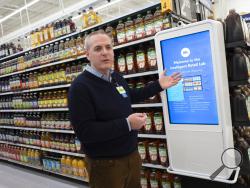 Mike Hanrahan, CEO of Walmart's Intelligent Retail Lab, discusses a kiosk that describes to customers the high technology in use at a Walmart Neighborhood Market, Wednesday, April 24, 2019, in Levittown, N.Y. "If we know in real time everything that's happening in the store from an inventory and in stock perspective, that really helps us rethink about how we can potentially manage the store," said Hanrahan. (AP Photo/Mark Lennihan)