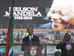 President Barack Obama delivers his speech next to a sign language interpreter during a memorial service at FNB Stadium in honor of Nelson Mandela on Tuesday, Dec. 10, 2013 in Soweto, near Johannesburg. The national director of the Deaf Federation of South Africa says a man who provided sign language interpretation on stage for Nelson Mandela’s memorial service in a soccer stadium was a “fake.”(AP Photo/ Evan Vucci) 