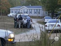 Law enforcement officials stand near a home on Callison Highway where six people were found dead, Tuesday evening, Oct. 29, 2013, in Greenwood, S.C. Authorities found the bodies Tuesday of four adults and two children, including the body of the man they believe called police, Greenwood County Sheriff's Office spokesman John Long told The Associated Press. (AP Photo/Index-Journal, Matt Bruce)