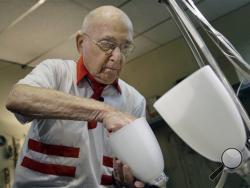 Lighting repair specialist Herman "Hy" Goldman, 101, refurbishes a light fixture in his workshop at Capitol Lighting where he has worked for 73 years, Monday, Aug. 18, 2014, in East Hanover, N.J. Now that he has turned 101, Goldman who often said that he would retire when he reached 100, has changed his mind. He still drives himself to work four days a week. (AP Photo/Mel Evans)