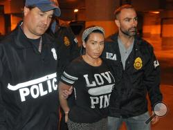 Samantha Barbash, center, is escorted by law enforcement officers following her arrest in New York. Barbash is allegedly part of a crew of New York City strippers who scammed wealthy men by drugging them and running up extravagant bills at topless clubs while they were in a daze, according to authorities. (AP Photo/DEA)
