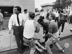 In this Sept. 14, 1989, file photo, Mayor Jerry Abramson, left, checks on one of the victims of the shooting spree at the Standard Gravure printing plant in downtown Louisville, Ky. Eight were killed and 12 injured by fellow employee Joseph Wesbecker, who also turned the gun on himself. (Gary S. Chapman/Louisville Courier-Journal via AP)