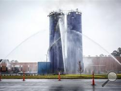 In this photo taken Monday, Dec. 7, 2015, a constant streams of water continues to be applied to a silo fire in Farmville, N.C. The silo full of dehydrated sweet potatoes has been smoldering in the town an hour east of Raleigh since at least the week of Thanksgiving, said Farmville town manager David Hodgkins. (Joe Pellegrino/The Daily Reflector via AP) 