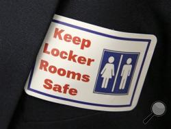 In this Jan. 27, 2016 file photo, a sticker that reads, "Keep Locker Rooms Safe," is worn by a person supporting a bill that would eliminate Washington's new rule allowing transgender people use gender-segregated bathrooms and locker rooms in public buildings consistent with their gender identity, at the Capitol in Olympia, Wash. (AP Photo/Ted S. Warren, File)
