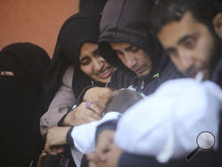 Palestinians mourn for relatives killed in the Israeli bombardment of the Gaza Strip outside a morgue in Khan Younis on Sunday, Jan. 7, 2024. (AP Photo/Mohammed Dahman)
