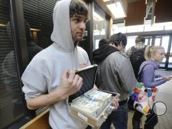 University of Utah student Luke Mughal holds a briefcase full of one-dollar bills as he waits in a long line to pay his tuition at the Student Services Building on the University of Utah campus in Salt Lake City, Utah Tuesday, Jan. 21, 2014. Mughal is paying his tuition in one-dollar bills to protest the high cost of tuition. (AP Photo/The Salt Lake Tribune, Steve Griffin) 