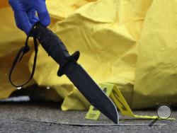 In this Tuesday, June 2, 2015 photo, law enforcement officials lift a knife that was believed to be held by Usaama Rahim, who police shot earlier in the day on Washington Street, in Boston's Roslindale neighborhood. (Mark Garfinkel/Boston Herald via AP) 