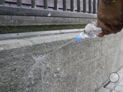In this Thursday, July 30, 2015, photo, Mohammed Nuru, director of San Francisco Public Works, demonstrates how water bounces off a wall covered with repellant paint outside a Mission District transit station in San Francisco. San Francisco now has multiple public walls covered with a repellant paint that makes pee spray back on the person's shoes and pants. (AP Photo/Eric Risberg)