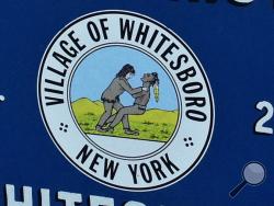 In this July 16, 2015 file photo, a welcome sign on the village green in Whitesboro, N.Y., displays the village seal. The upstate New York village of Whitesboro has confirmed that it will change its official logo a day after the image, which appears to show a white man throttling an Indian, was ridiculed on Comedy Central's "The Daily Show." (Observer-Dispatch via AP)