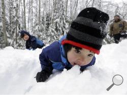 Leon Perkins, 3, leans forward to take a bite of snow as he plays with his brother Conner, left, 2, and his father Erin, Tuesday, Dec. 22, 2015, at Snoqualmie Pass, Wash. The Seattle family headed to the mountains Tuesday to enjoy the new snow that fell overnight. A weather pattern that could be associated with El Nino has turned winter upside-down across the U.S. during a week of heavy holiday travel. (AP Photo/Elaine Thompson)