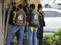Bikers congregate against a wall while authorities investigate a Twin Peaks restaurant Sunday, May 17, 2015, in Waco, Texas. Waco Police Sgt. W. Patrick Swanton told KWTX-TV there were "multiple victims" after gunfire erupted between rival biker gangs at the restaurant. (Rod Aydelotte/Waco Tribune-Herald via AP)