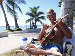 In this photo taken Tuesday Jan. 26, 2016, Kent Terada shows the shaka or "hang loose" sign while sitting at Ala Moana Beach Park in Honolulu. A new study looking at the five elements of a well ordered life, such as financial security, sense of community and purpose, ranks Hawaii just ahead of Alaska. (AP Photo/Audrey McAvoy)