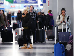 A traveler, right, checks on her cellphone as other travelers walk through Terminal 3 at O'Hare International Airport in Chicago, Thursday, Dec. 22, 2022. (AP Photo/Nam Y. Huh)
