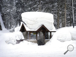 A person sits in a snow-covered bus stop Friday, Feb. 24, 2023, in Olympic Valley, Calif. California and other parts of the West are facing heavy snow and rain from the latest winter storm to pound the United States. (AP Photo/John Locher)