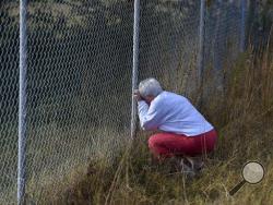 Frances Bradley prays at the fence adjoining their properties in Woodruff, S.C. Sunday, Nov. 6, 2016. Kohlhepp, accused of holding a woman chained inside a storage container, was due in court for a bond hearing Sunday after investigators say he confessed to an unsolved quadruple murder that happened 13 years ago. He's also charged with the woman's kidnapping, and prosecutors say more charges are expected. (AP Photo/Richard Shiro)