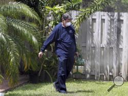 In this photo taken April 12, 2016, Giraldo Carratala, an inspector with the Miami- Dade County, Fla. mosquito control unit, sprays pesticide in the yard of a home in Miami, Fla. (AP Photo/Lynne Sladky)