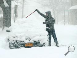 Harry Dobin, Long Island, New York, clears the snow from the roof of his car on Third Street in Bloomsburg Tuesday morning. (Press Enterprise/Keith Haupt)