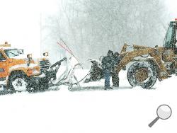 Bloomsburg town employees work to get a plow truck out of a ditch along Poplar Street in Bloomsburg Tuesday morning. (Press Enterprise/Keith Haupt)
