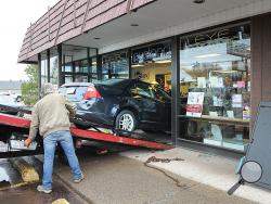 A Ford Fusion is pulled from the interior of this Eyeland Store along Front Street in Berwick Thursday afternoon. (Press Enterprise/Keith Haupt)