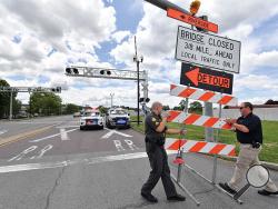 Mahoning Township Sgt. Matt Grist, and Danville Sgt. J.D. Stanley move a PennDOT sign into the roadway at the intersection with Route 11 on Route 54 to prevent drivers from going south on Route 54 to the Danville Riverside Bridge which is closed Friday afternoon. Only north bound passenger cars are allowed to come over the bridge from Riverside as Norfolk Southern has the railroad crossing close while they rebuild it. (Press Enterprise/Jimmy May)