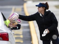 Cafeteria worker Cathy Piluso hands out free meals at Bensalem High School in Bensalem, Pa., Thursday, March 19, 2020.Pennsylvania reported another big jump in confirmed coronavirus Thursday. The state Department of Health reported that cases topped 180, up 40%. (AP Photo/Matt Rourke)