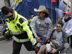 Medical responders run an injured man past the finish line the 2013 Boston Marathon following an explosion in Boston, Monday, April 15, 2013. Two explosions shattered the euphoria of the Boston Marathon finish line on Monday, sending authorities out on the course to carry off the injured while the stragglers were rerouted away from the smoking site of the blasts. (AP Photo/Charles Krupa)