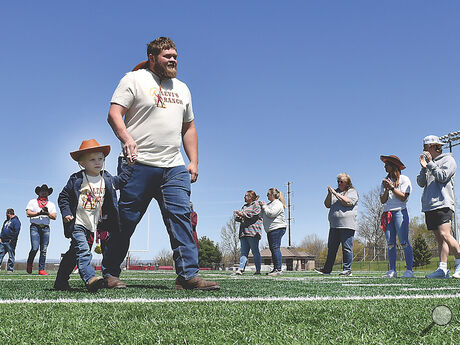 Levi Barben, 4, holds the hand of his father David Barben while walking across Danny Hale Field at Redman Stadium through family, friends and Bloomsburg University students while on the way to reveal his Make A Wish Thursday.