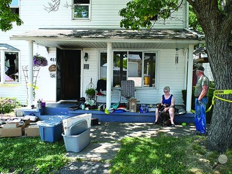 Kathy and Bill Gulliver with their dog Brandi sit on the front porch of their home after a fire early Wednesday morning on Warren Street in Nescopeck, trying to salvage what they can from the blaze.