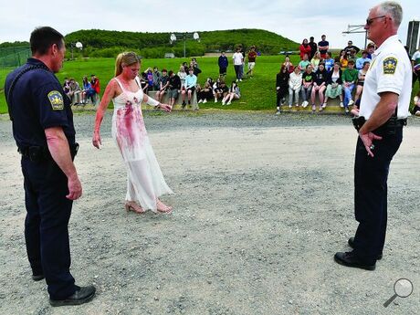Millville School District resource officer Brad Sharrow, left, gives a mock sobriety test to 11th grade student Olivia Kile while standing in front of Hemlock Township Police Chief Michael VanDine and her classmates during a mock crash meant to simulate the dangers of drunken driving on Thursday afternoon next to the school's sports stadium. 