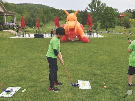 Liberty Valley Intermediate School fifth grade students, from left, Matt Styer, Noah Lee and Hunter Auman work to chip balls into the mouth of an inflatable dragon at the Frosty Valley Resort during Tuesday’s green field trip. 
