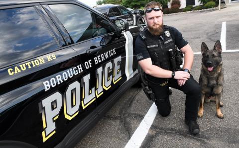 Berwick police officer Jeremy Mulders poses with the police dog Dacan outside the police station Monday evening.