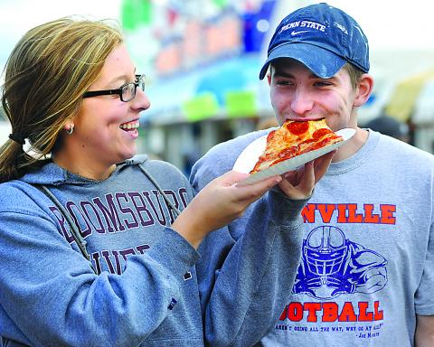 Erin Sidler laughs as Nick LeVan takes a bite of pizza as the two walk through the Bloomsburg Fair Sunday. (Press Enterprise/M.J. Mahon)