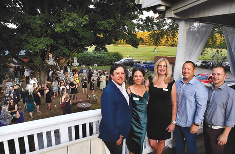 For the Cause gala Three men and two women, all well-dressed, pose in front of a crowd at a party.
