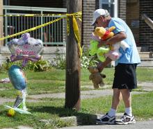 Paul Laughlin, 57, places stuffed animals on Sunday, Aug. 11, 2019 outside a home at 1248 West 11th St. in Erie, Pa., where multiple people died in an early-morning fire. (Greg Wohlford/Erie Times-News via AP)