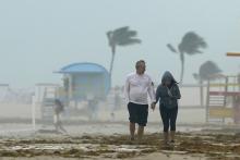 A couple walks along the beach during a downpour, Sunday, Nov. 8, 2020, on Miami Beach, Florida's famed South Beach. A strengthening Tropical Storm Eta cut across Cuba on Sunday, and forecasters say it's likely to be a hurricane before hitting the Florida Keys Sunday night or Monday. (AP Photo/Wilfredo Lee)