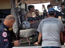 British backpacker Sam Derry-Woodhead, second left, sits in a rescue helicopter as he is tended to by ambulance personnel.