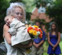 Christine Swidorsky carries her son and the couple's best man, Logan Stevenson, 2, down the aisle to her husband-to-be Sean Stevenson during the wedding ceremony on Saturday, Aug. 3, 2013 in Jeannette, Pa. Logan stood with his grandmother, Debbie Stevenson, during a 12-minute ceremony uniting Logan's mother and his father. The boy has leukemia and other complications. 