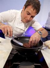 A new Cultured Beef Burger made from cultured beef grown in a laboratory from stem cells of cattle, is cooked by chef Richard McGeown during the world's first public tasting of the product held in London Monday. The cultured beef product was developed by Professor Mark Post, not pictured, of Netherland's Maastricht University. The cultured beef could help solve the coming food crisis and combat climate change, say the producers of the burger, which cost $332,000 to make. (AP Photo/David Parry)