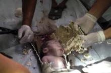 In this still image taken from video from Saturday May 25, 2013, rescue workers cut away parts of a sewage pipe where a newborn baby was trapped in Pujiang in east China's Zhejiang province. Chinese firefighters have rescued a newborn boy from a sewer pipe below a squat toilet, sawing out an L-shaped section and then delicately dismantling it to free the trapped baby, who greeted the rescuers with cries. A tenant heard the baby’s sounds in the public restroom of a residential building in Zhejiang province.