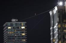 Daredevil Nik Wallenda makes his tightrope walk uphill at a 19-degree angle, from the Marina City west tower across the Chicago River to the top of the Leo Burnett Building, past the Aqua Building, background, Sunday, Nov. 2, 2014, in Chicago. (AP Photo/Charles Rex Arbogast)
