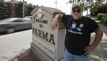 Douglas Odolecki poses next to a "Welcome to Parma" sign Wednesday, June 18, 2014, in Parma, Ohio. Odolecki was cited Friday for holding a sign that said: "Check point ahead! Turn now!" (AP Photo/Tony Dejak)